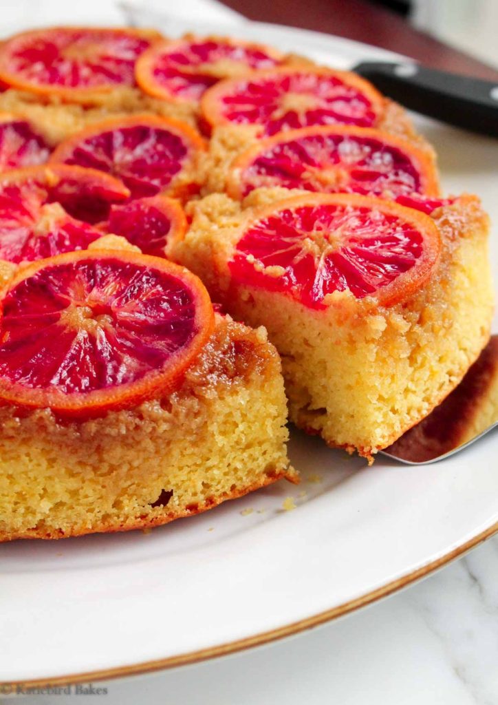 A slice of Blood Orange olive oil Upside-Down Cake being removed from the plate