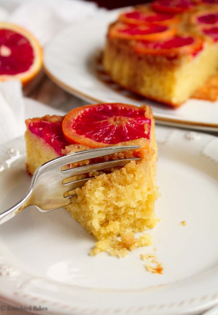 A fork cutting into a slice of upside down blood orange olive oil cake