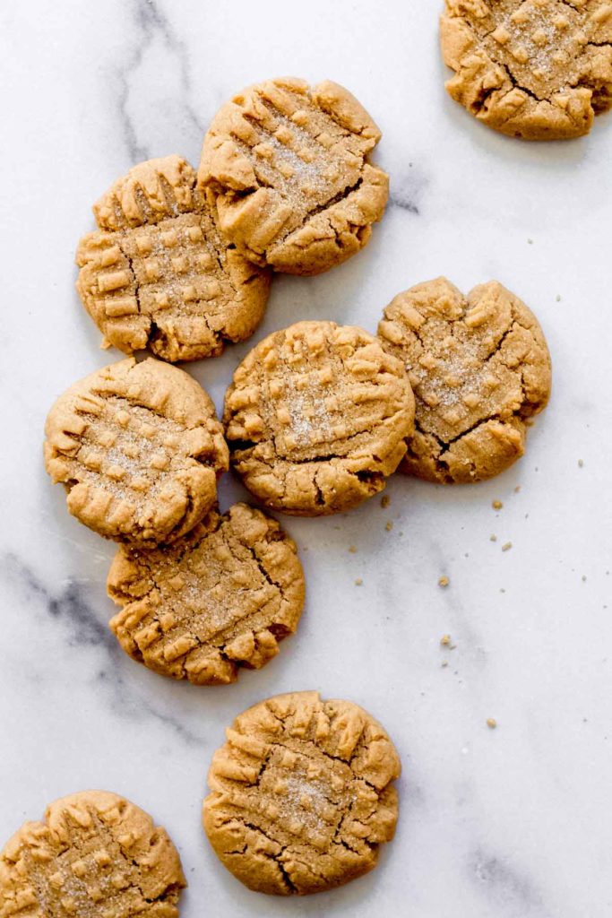 a few peanut butter cookies piled on top of each other on a white marble surface