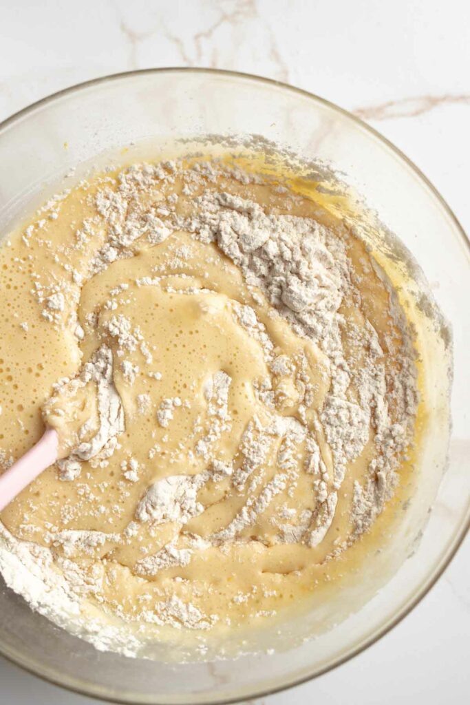 muffin batter mid-stir in a large glass bowl