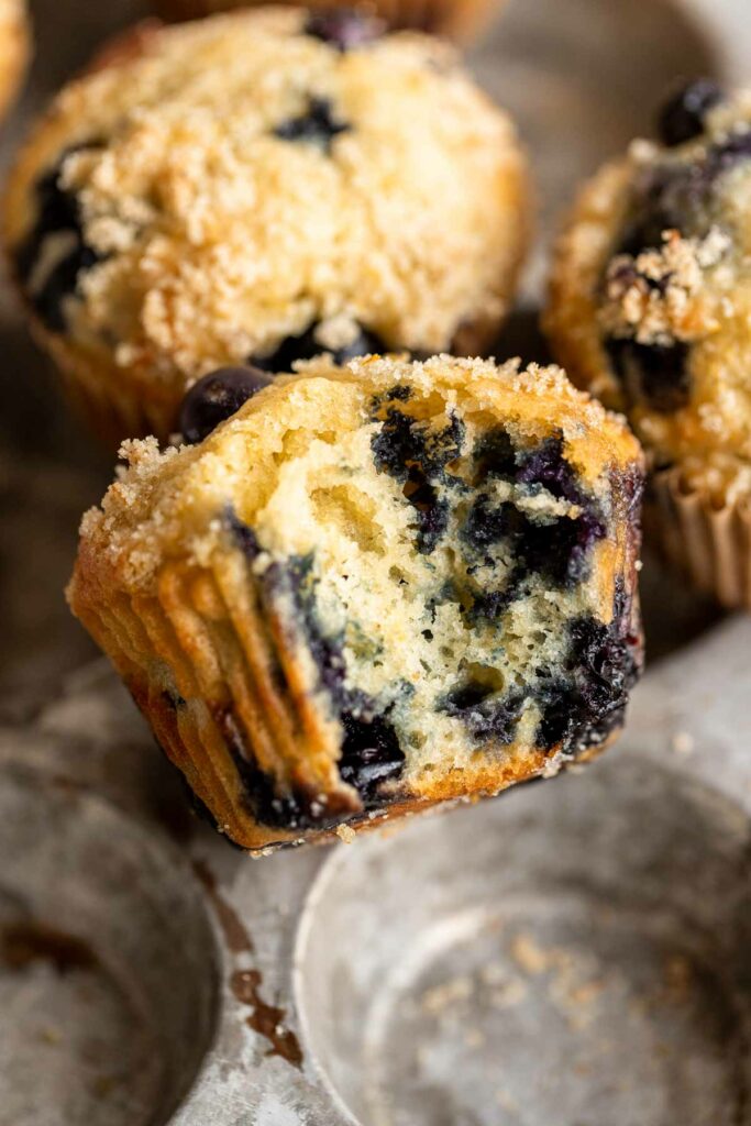 close up view of a blueberry muffin with a bite taken out of it to see the fluffy interior texture