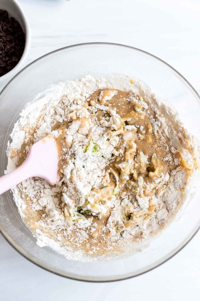 flour being mixed into zucchini muffin batter 