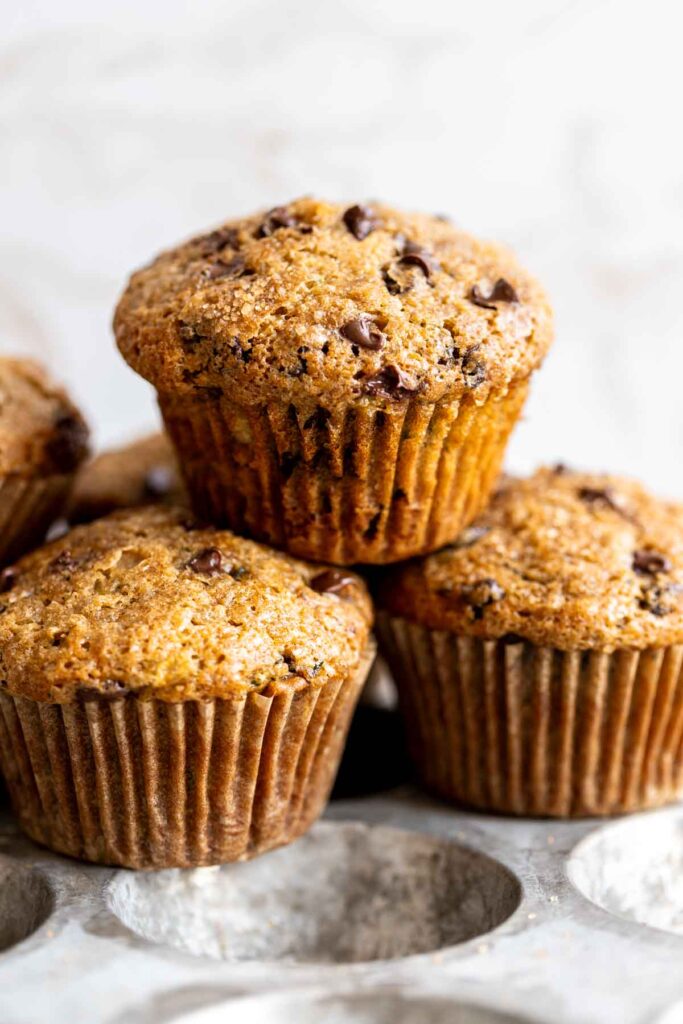 3 zucchini chocolate chip muffins stacked on top of each other against a white background