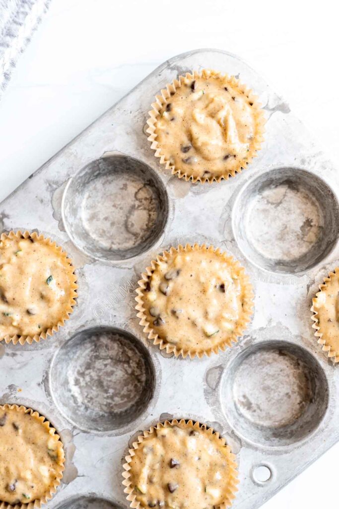 muffin batter in parchment liners in a muffin tin