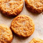 close up view of several pumpkin snickerdoodle cookies arranged on a flat white surface