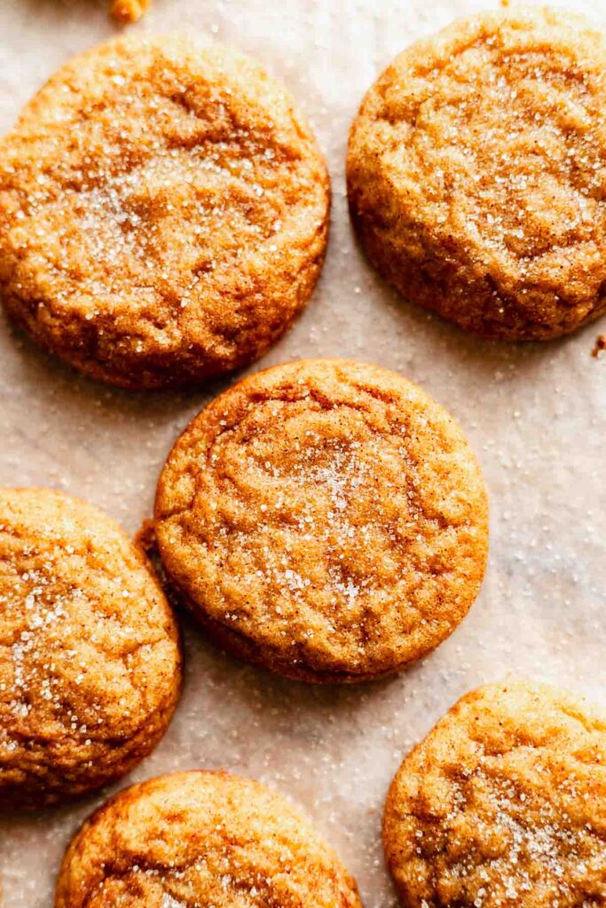 close up view of several pumpkin snickerdoodle cookies arranged on a flat white surface